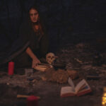 Dark image of a person consulting old books and a skull